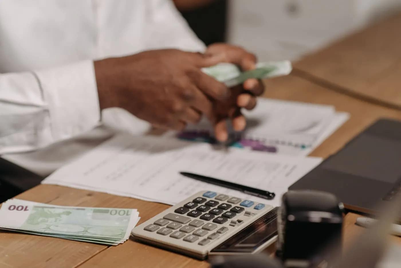 Manos contando billetes junto a una calculadora durante una revisión de operaciones